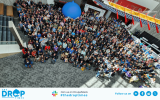 Group photo from DrupalCon Portland 2024 where attendees gather in the corridor and a giant Drupal Icon ballon is seen in the backdrop