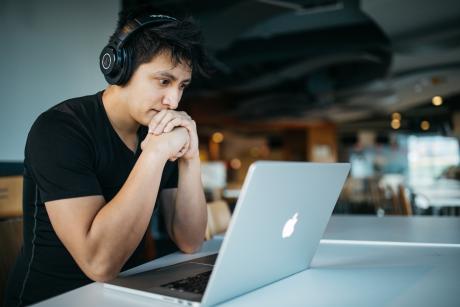 A man listening to something while looking at his laptop
