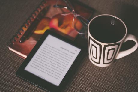 Black Kindle on a book and near a mug